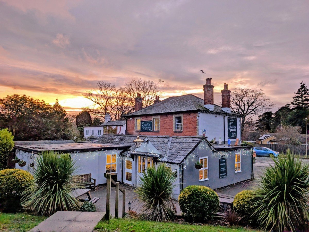 The Fox and Hounds pub next to the Basingstoke Canal at sunset with lights visible through the windows of this two storey building