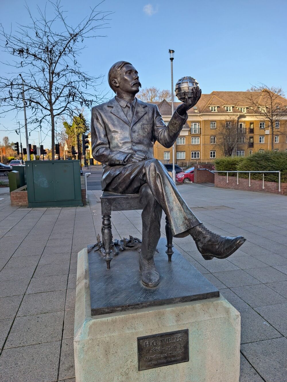 Close up of HG Wells statue in Woking, featuring a man sat down holding a circle