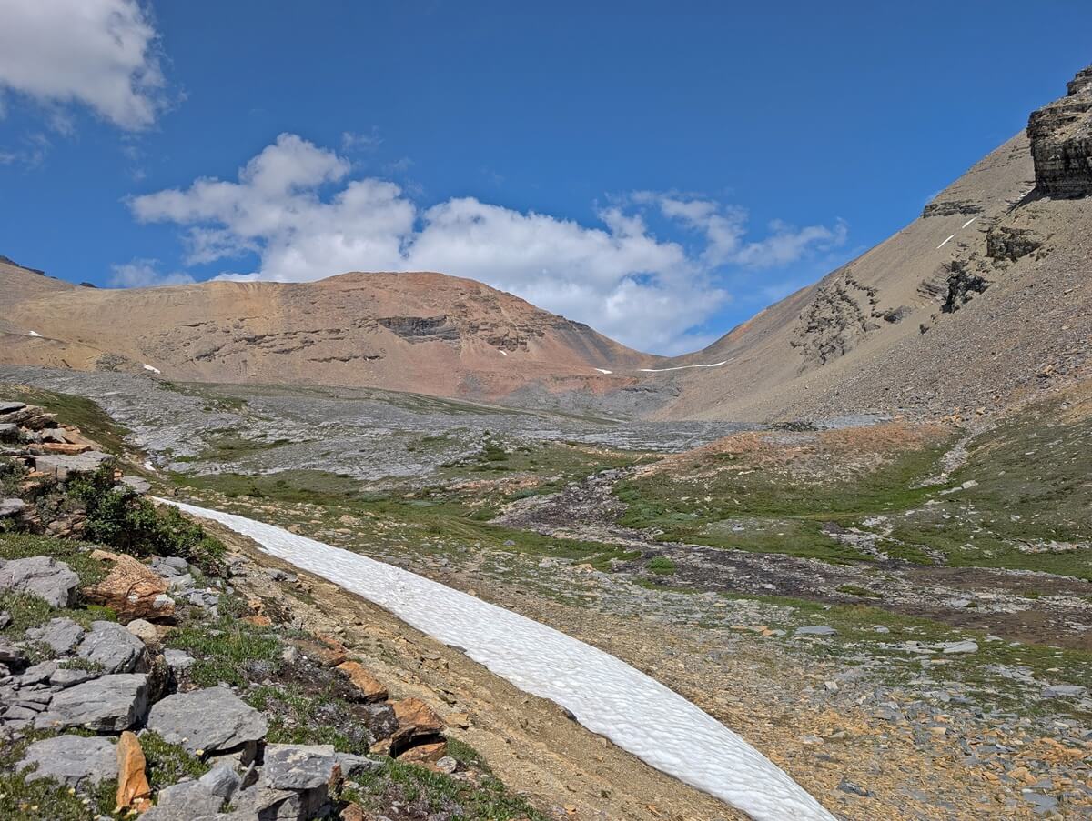 Looking across meadows towards the end of Snowbird Pass saddle, a low section between two mountains