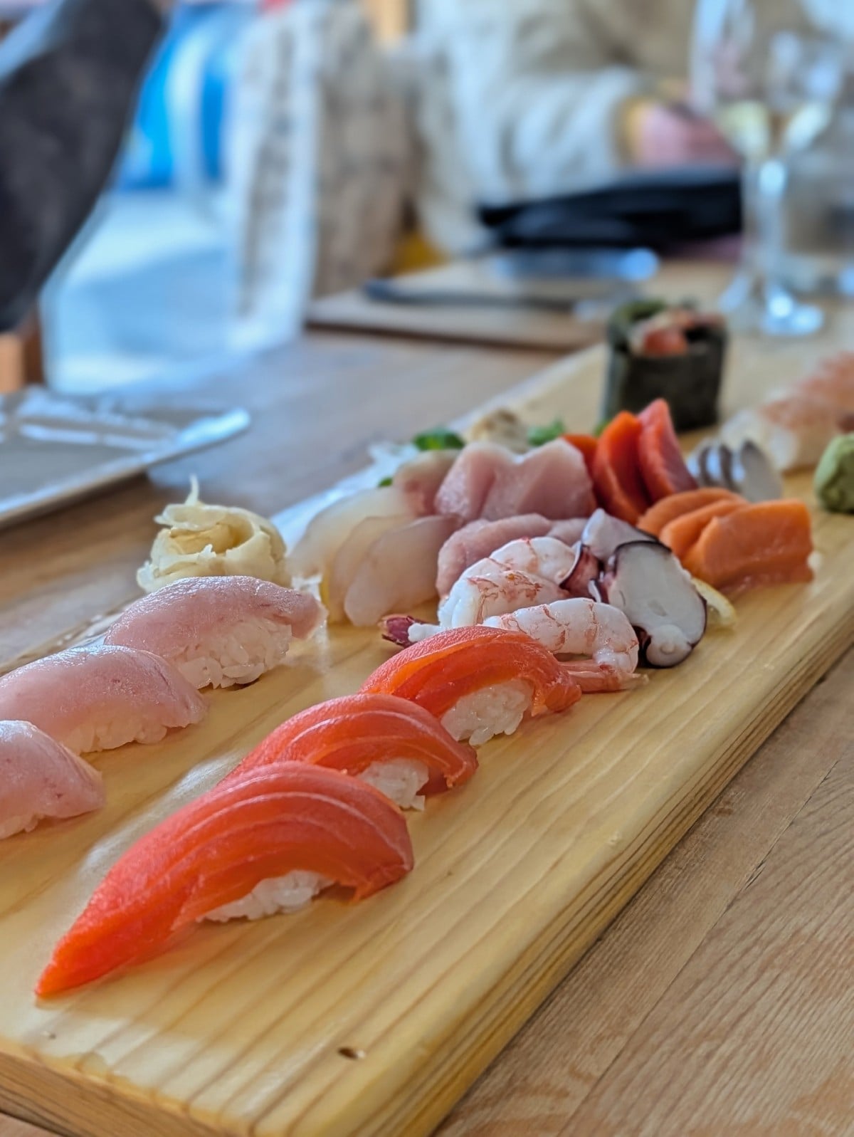 Close up of sushi platter at Fukasaku featuring salmon, tuna, prawns, octopus on wooden plank