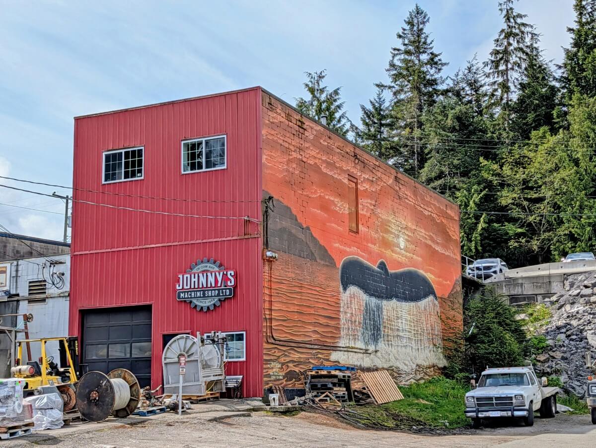 Sunset whale tail artwork on side of Johnny's Machine Shop Limited in Cow Bay, Prince Rupert