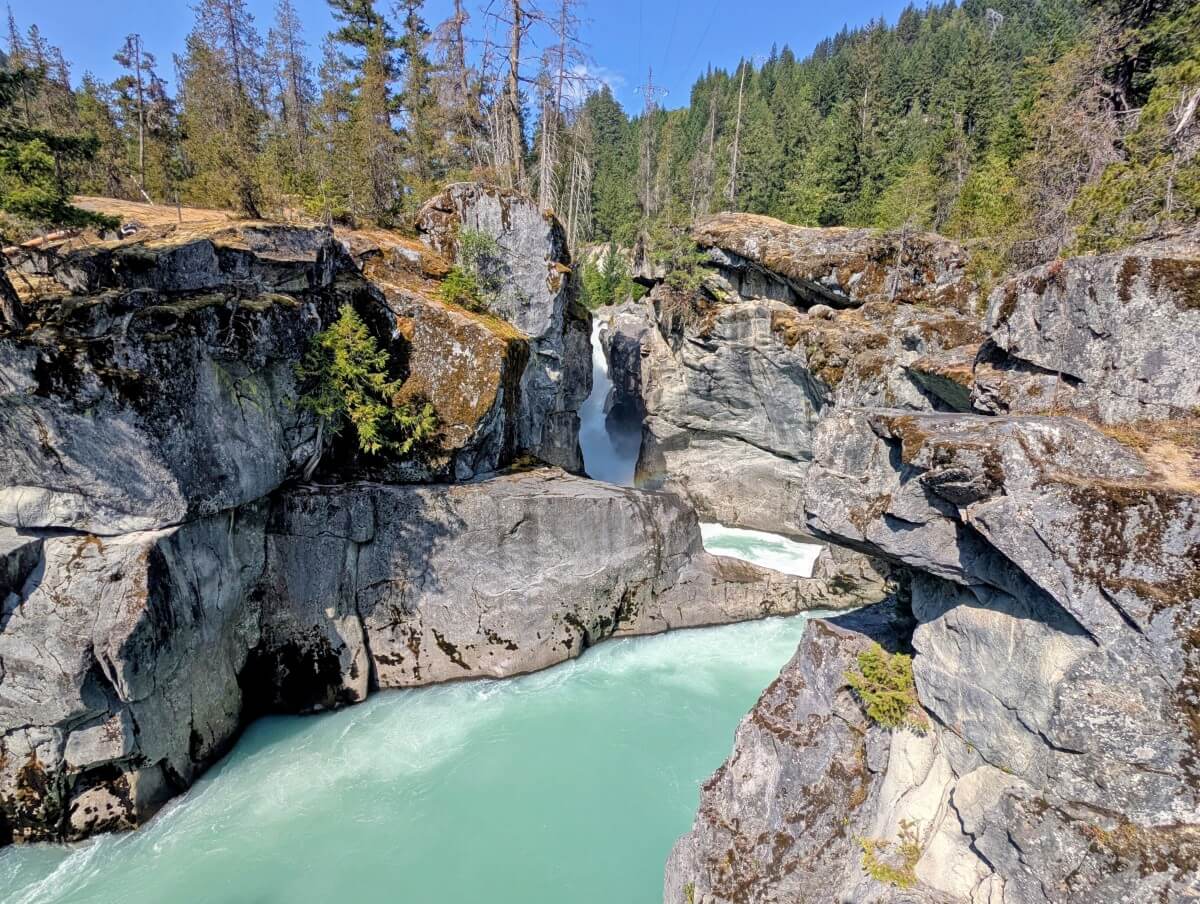 Looking towards Nairn Falls, a milky turquoise coloured waterfall cascading into a rocky canyon 