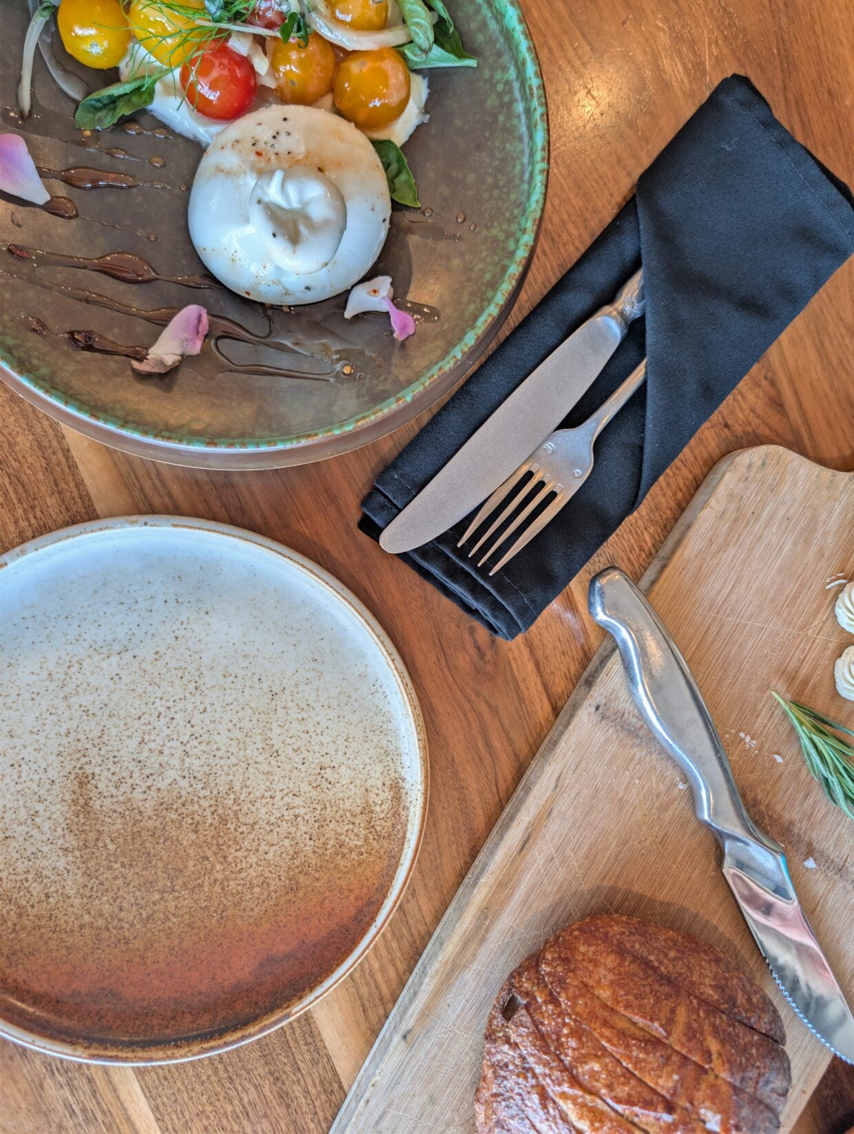 Overhead view of burrata salad plate at Terra with knife, fork, plate and bread