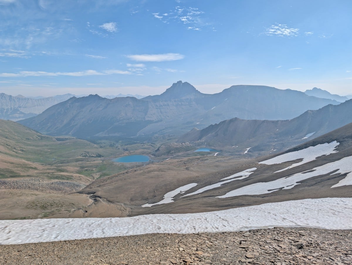 View from Skyline ridge over two turquoise coloured alpine lakes backdropped by mountains, with a band of snow in the foreground
