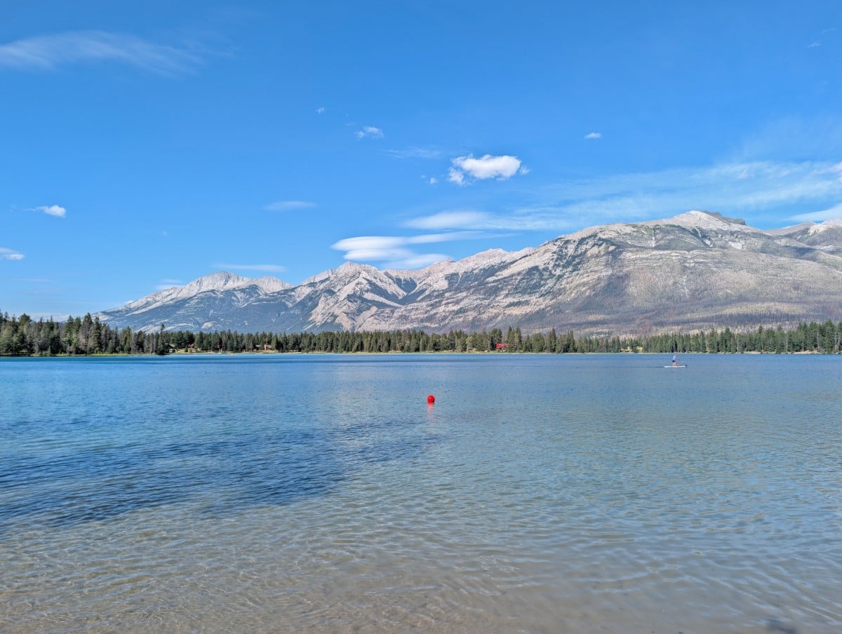Calm Edith Lake, tinged with blue and backdropped by a line of mountains