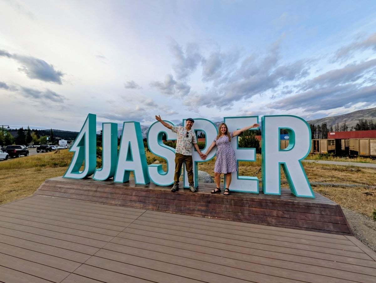 Gemma and JR stand in front of a large Jasper sign and pose