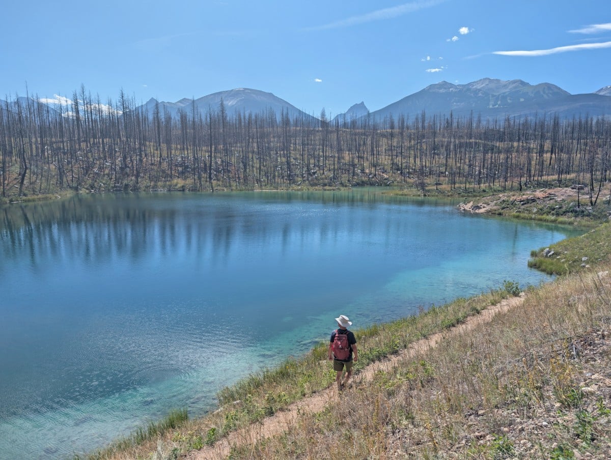JR walks on a lower path next to a turquoise coloured lake on the Valley of Five Lakes Trail in Jasper National Park