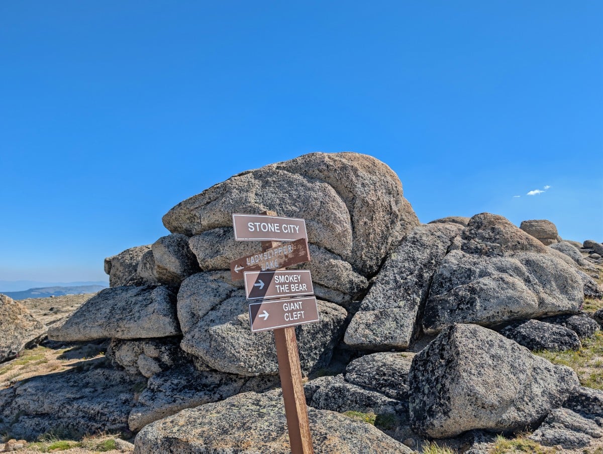 Close up of Stone City, Ladyslipper Lake, Smokey the Bear, Giant Cleft wooden signs in front of rock pile