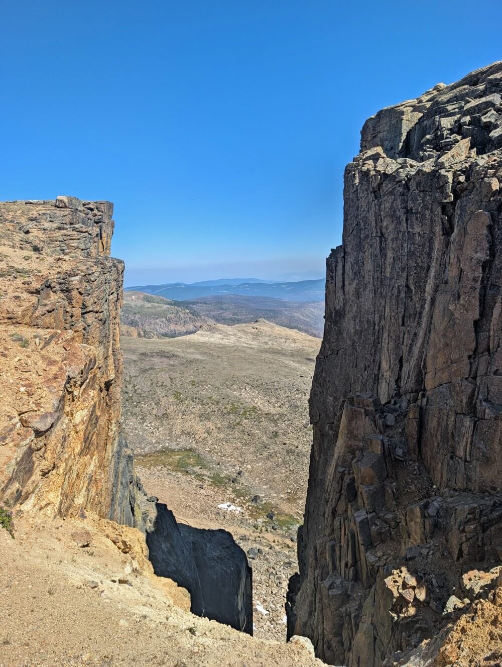 Steep vertical rock walls with mountain views in background on the Rim Trail